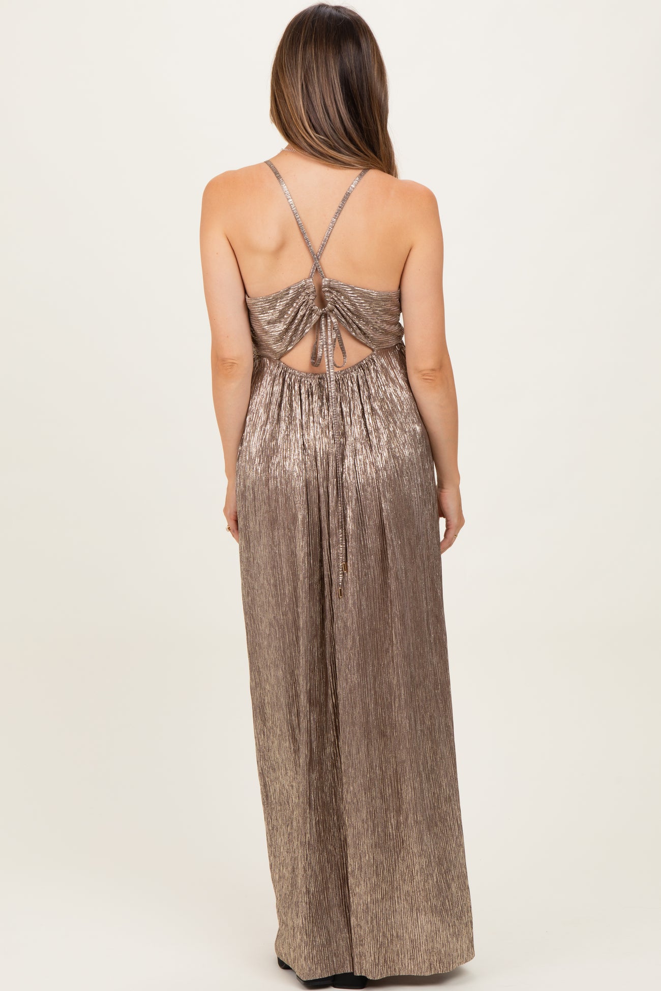 woman wearing a shiny gold maternity maxi dress with crisscross back and adjustable straps