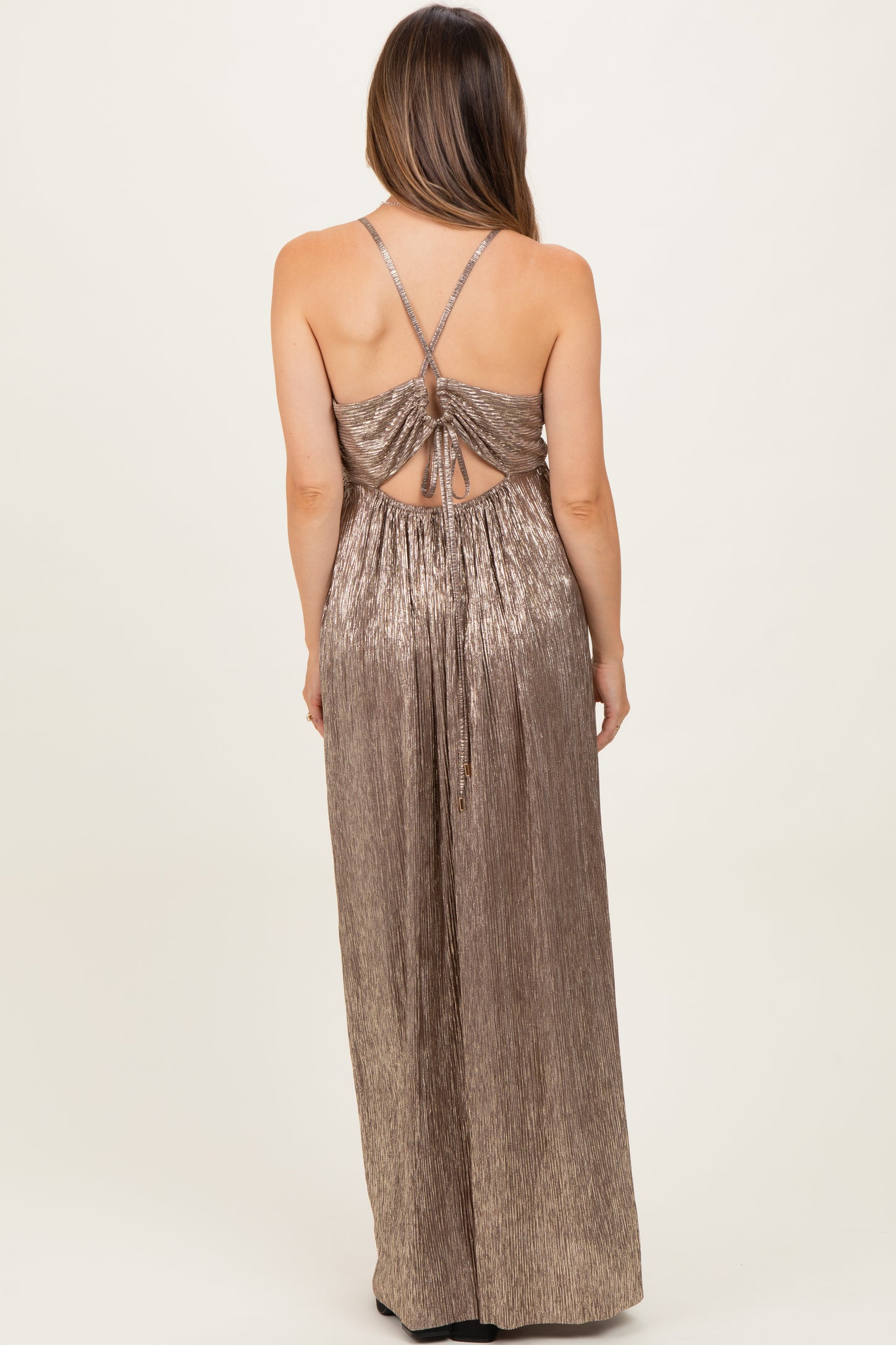 woman wearing a shiny gold maternity maxi dress with crisscross back and adjustable straps