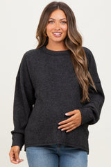 woman wearing a dark gray oversized maternity sweater and holding her baby bump