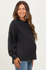woman wearing a dark gray oversized maternity sweater and showing her baby bump
