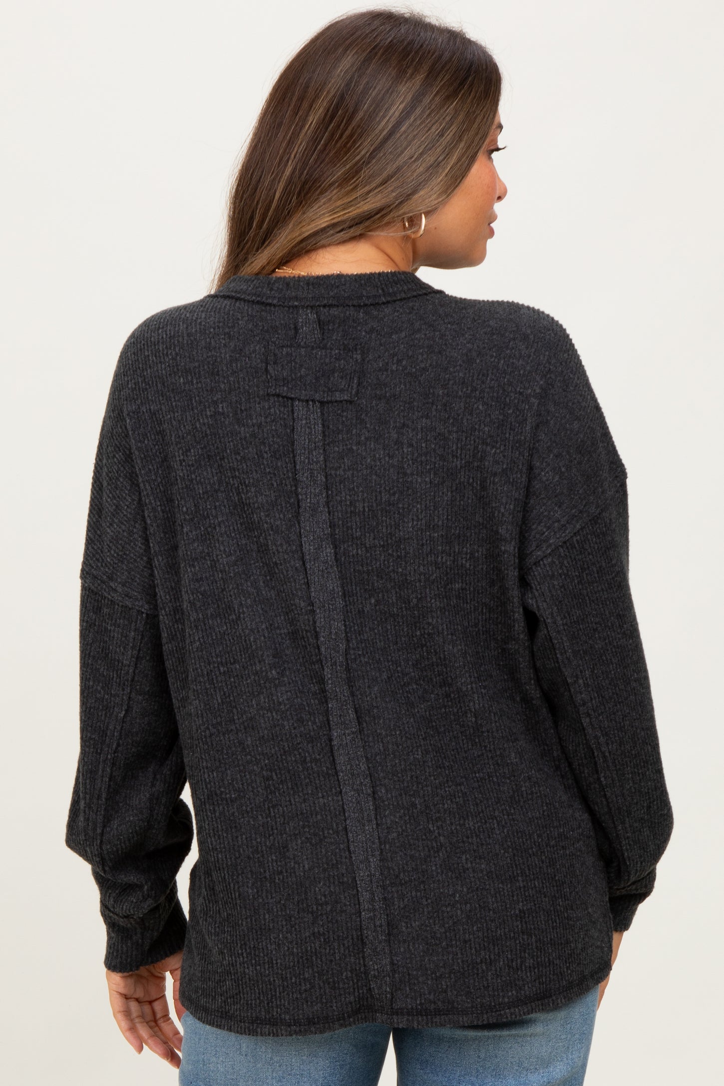woman wearing a dark gray maternity sweater with a back seam detail