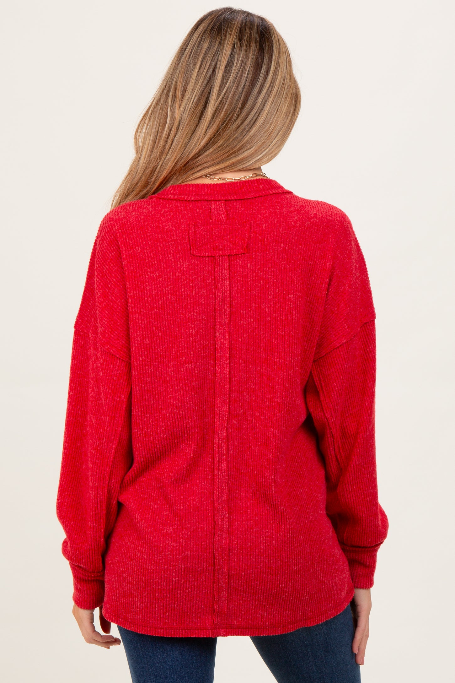 woman wearing a red oversized maternity sweater with a back seam detail and relaxed fit