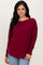 woman wearing a burgundy long sleeve top with a relaxed fit and scoop neckline, styled with light blue jeans