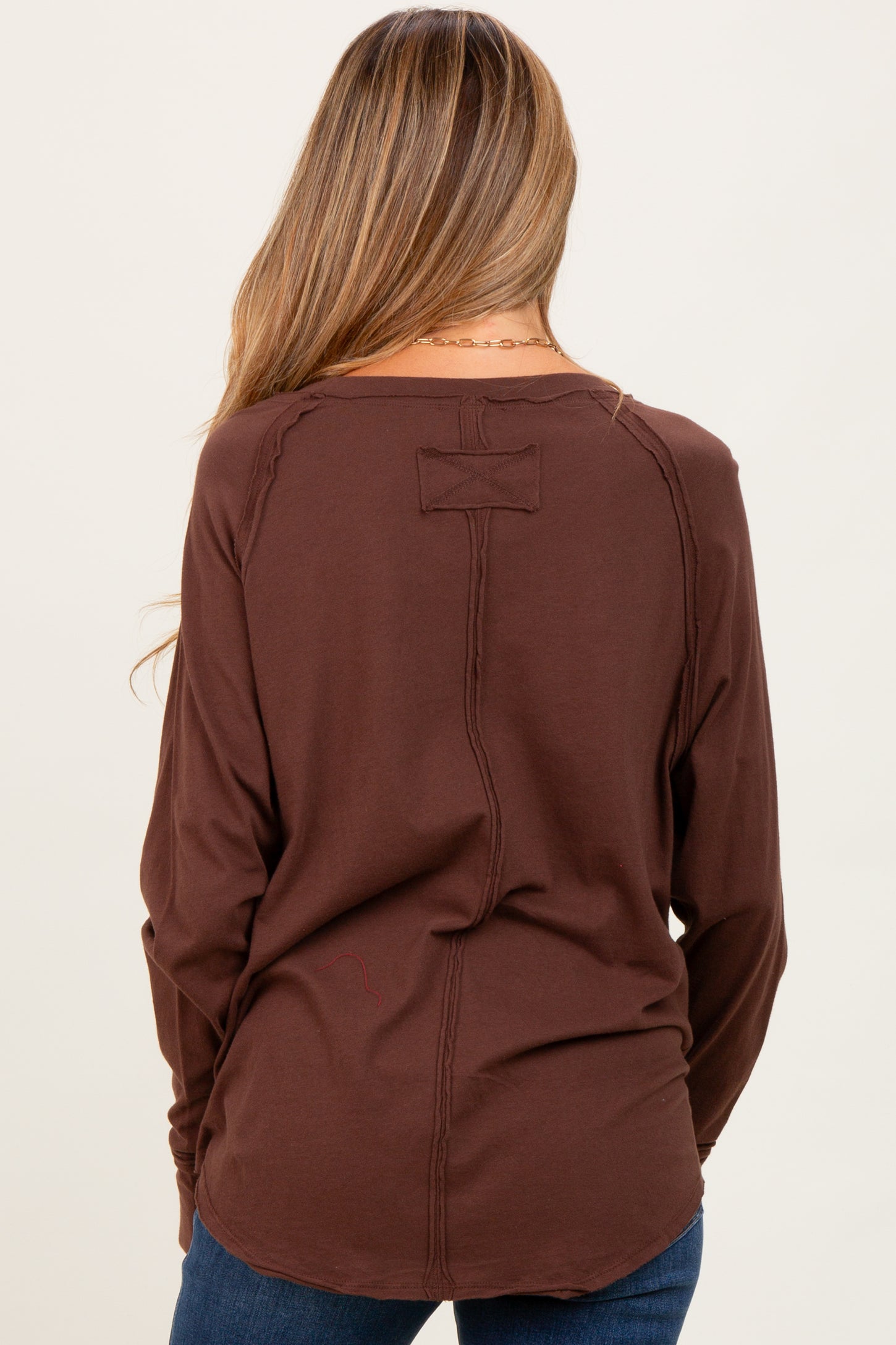 woman wearing a brown long sleeve maternity top with a relaxed fit and back seam detail