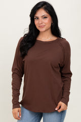 woman wearing a brown long sleeve top with a rounded neckline and relaxed fit, paired with light blue jeans