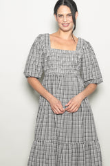 woman wearing a black and white checkered puff sleeve dress with a square neckline and tiered skirt