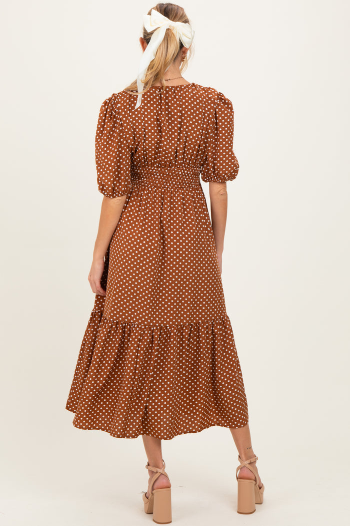 woman wearing a brown polka dot maternity dress with puff sleeves and a tiered skirt, showing her baby bump from behind