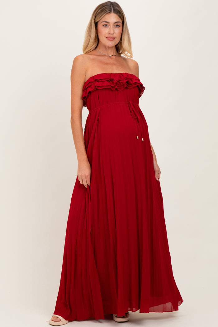 woman wearing a red strapless maternity dress with ruffles and a flowing skirt, highlighting her baby bump