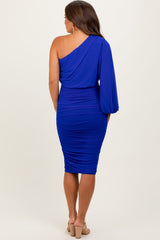 woman wearing a royal blue one-shoulder maternity dress with ruched details and a balloon sleeve, shown from the back