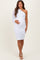 woman wearing a white one-shoulder ruched maternity dress and holding her baby bump