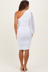 woman wearing a white one-shoulder maternity dress with ruched detailing and a sheer sleeve