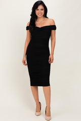 woman wearing a black off-the-shoulder fitted dress with ruching and a midi length