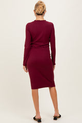 woman wearing a burgundy long sleeve ribbed maternity dress with a fitted silhouette and knee-length hem