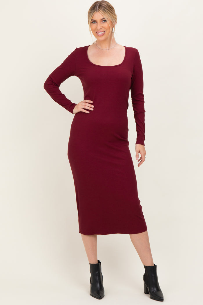 woman wearing a burgundy long sleeve fitted midi dress with a scoop neck and black ankle boots