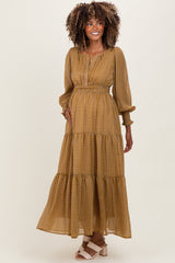 woman wearing a mustard patterned long sleeve maternity dress with an elastic waistband and tiered skirt, showing her baby bump