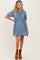 woman wearing a light denim maternity dress with puff sleeves and a tie neckline, showcasing her baby bump