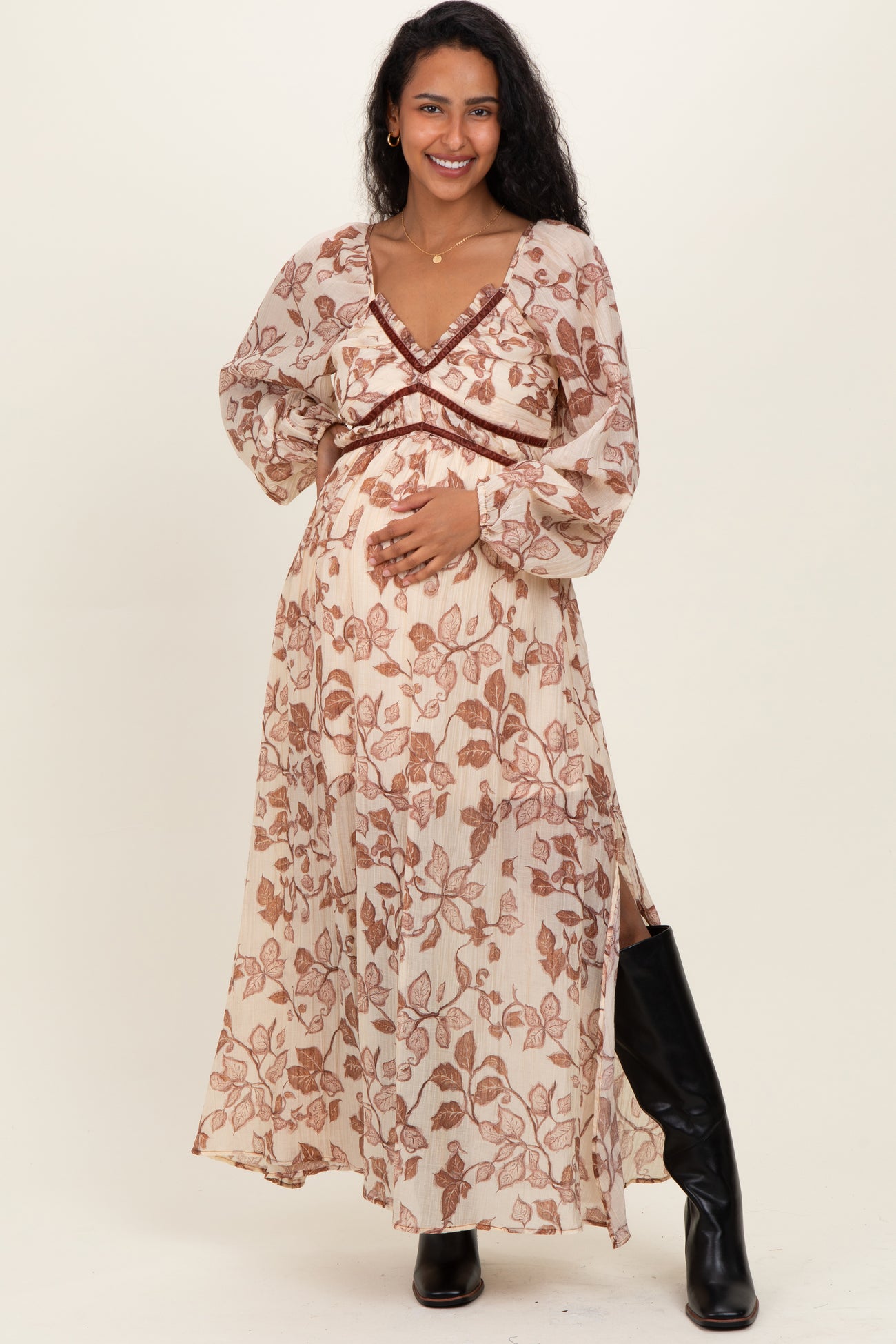 woman wearing a cream floral print maternity maxi dress, showcasing her baby bump with long sleeves and a deep v-neckline