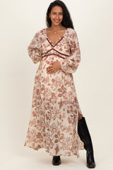 woman wearing a cream floral print maternity maxi dress, showcasing her baby bump with long sleeves and a deep v-neckline
