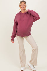 woman wearing a mauve maternity hoodie with a relaxed fit and beige ribbed maternity pants, showing her baby bump