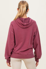 woman wearing a raspberry hoodie with a relaxed fit, showcasing the back design and long sleeves as maternity wear