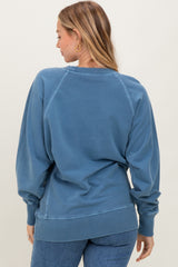 woman wearing a blue oversized sweatshirt with balloon sleeves and ribbed hem, viewed from the back
