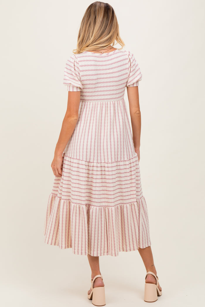 woman wearing a striped maternity maxi dress with tiered ruffles and short sleeves, showing her baby bump from the back