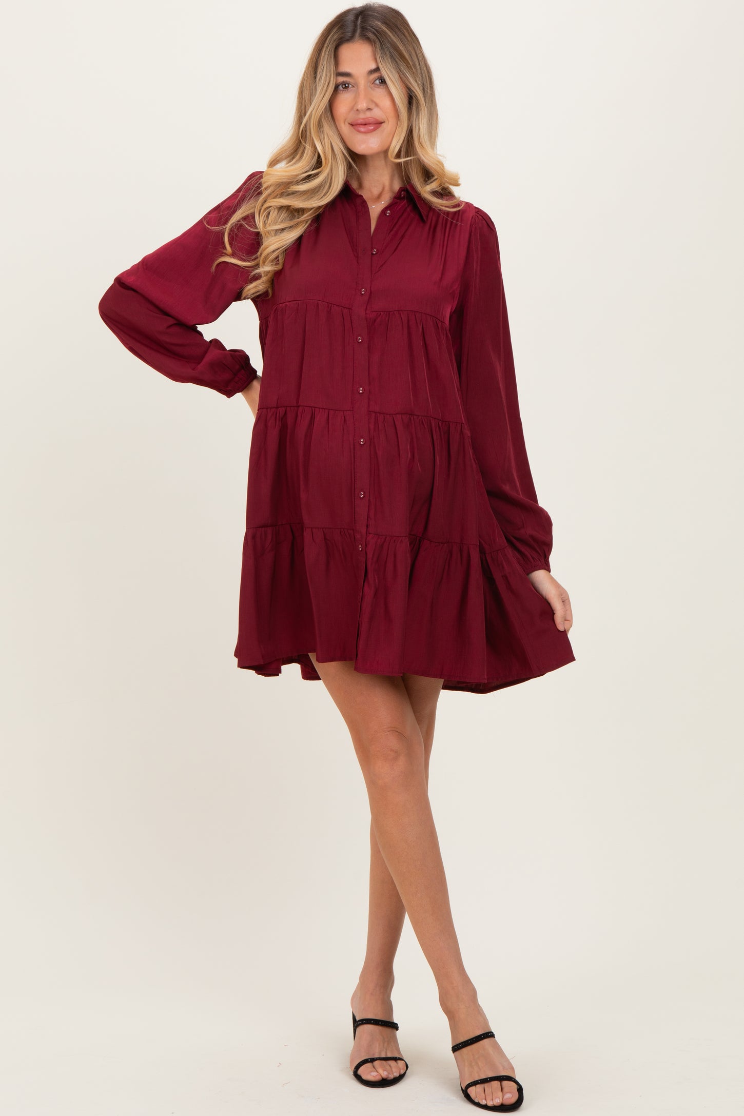 woman wearing a burgundy maternity dress with long sleeves and tiered ruffle details, showing a baby bump