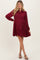 woman wearing a burgundy maternity dress with long sleeves and tiered ruffle details, showing a baby bump