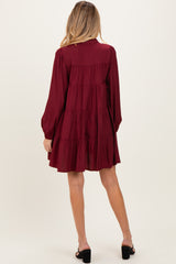 woman wearing a burgundy maternity dress with long sleeves and tiered ruffles, showing a flowing silhouette from the back