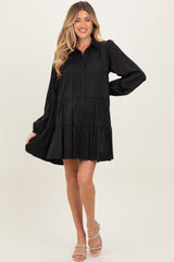 woman wearing a black tiered long sleeve maternity dress with button details and a flowing silhouette