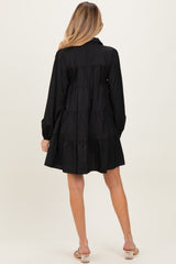 woman wearing a black maternity dress with tiered ruffles and long sleeves, viewed from the back