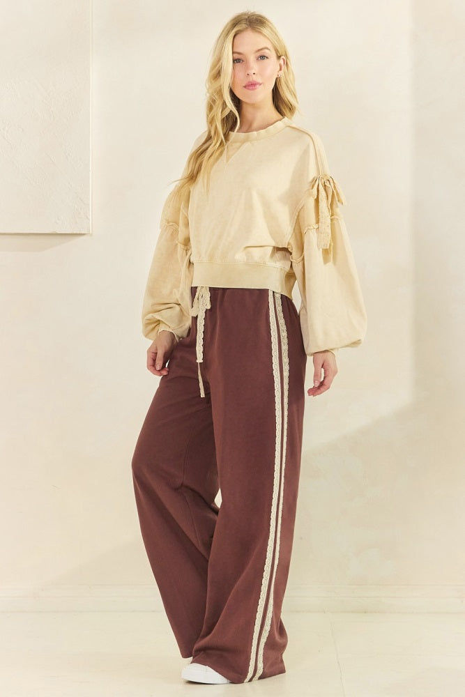 woman wearing a cream oversized sweatshirt with puff sleeves and brown sweatpants featuring side stripes