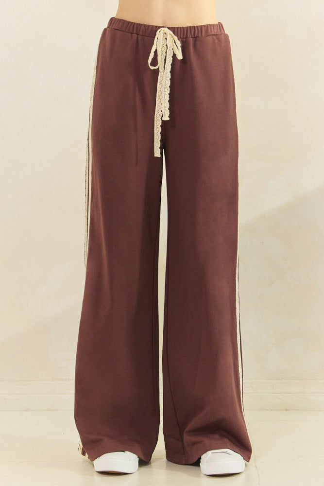 woman wearing maroon wide-leg pants with a decorative drawstring and side stripes
