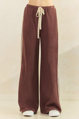 woman wearing maroon wide-leg pants with a decorative drawstring and side stripes