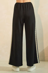 woman wearing black wide-leg pants with lace side details, viewed from the back