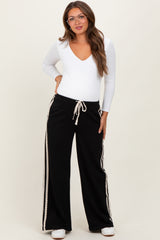 woman wearing a white long sleeve v-neck maternity top and black wide-leg maternity pants with side stripes