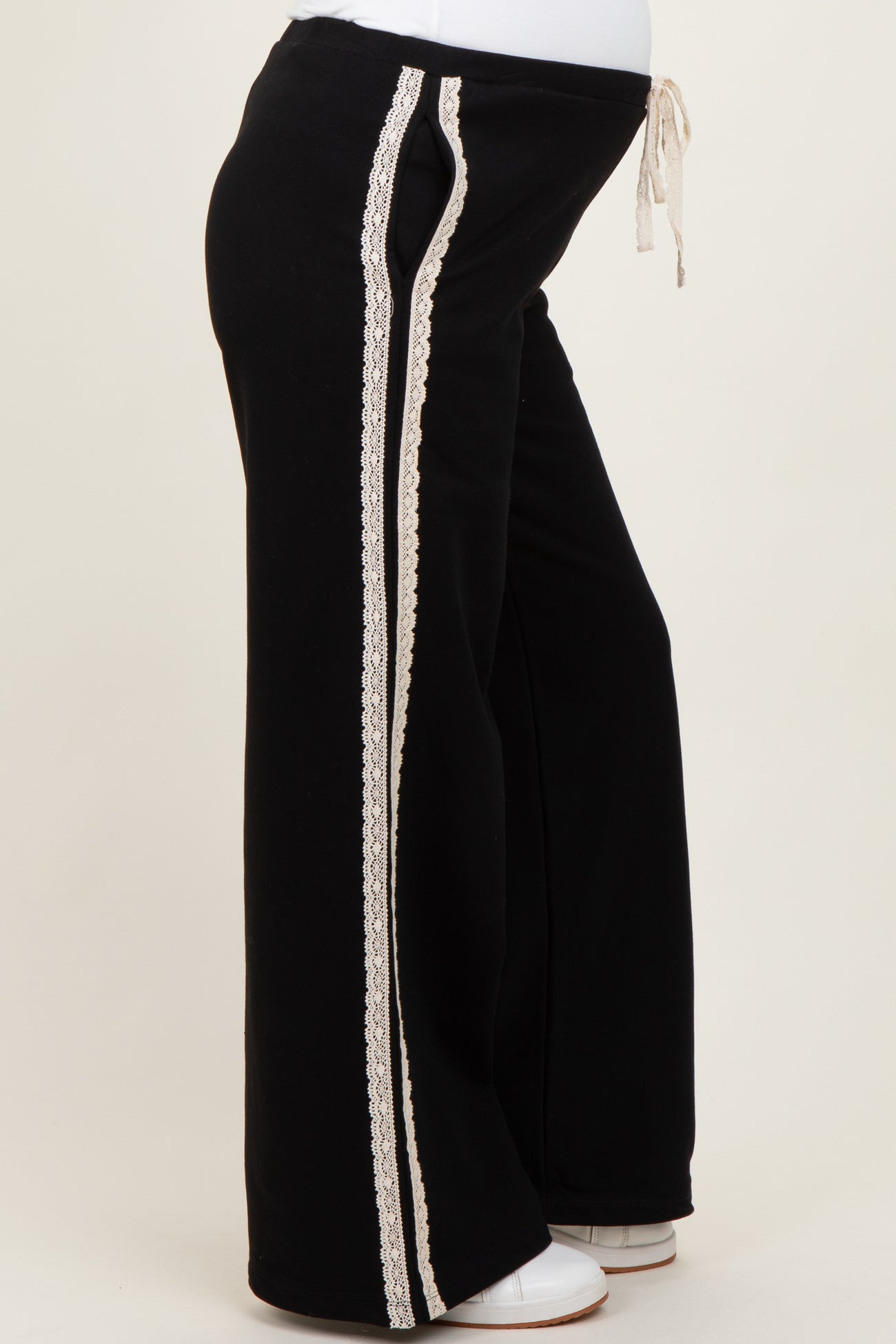 maternity wear in black sweatpants with lace side stripes, featuring a drawstring waist and a visible baby bump