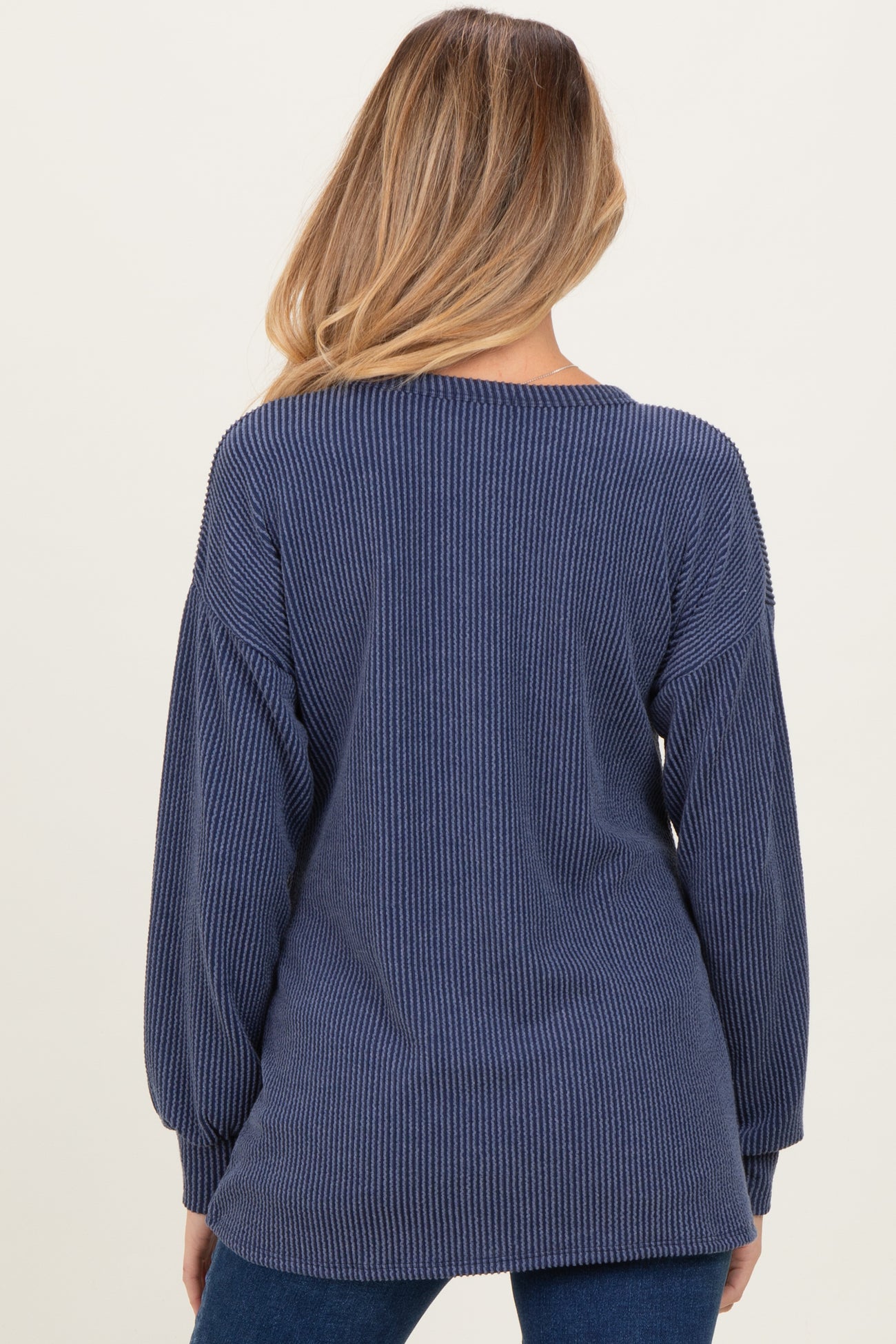 woman wearing a navy blue ribbed maternity sweater with balloon sleeves, showing the back view