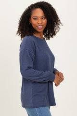 woman wearing a dark blue ribbed knit sweater with long sleeves and relaxed fit, smiling at the camera