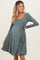 woman wearing a sage green long sleeve maternity dress with a tie at the waist and a visible baby bump