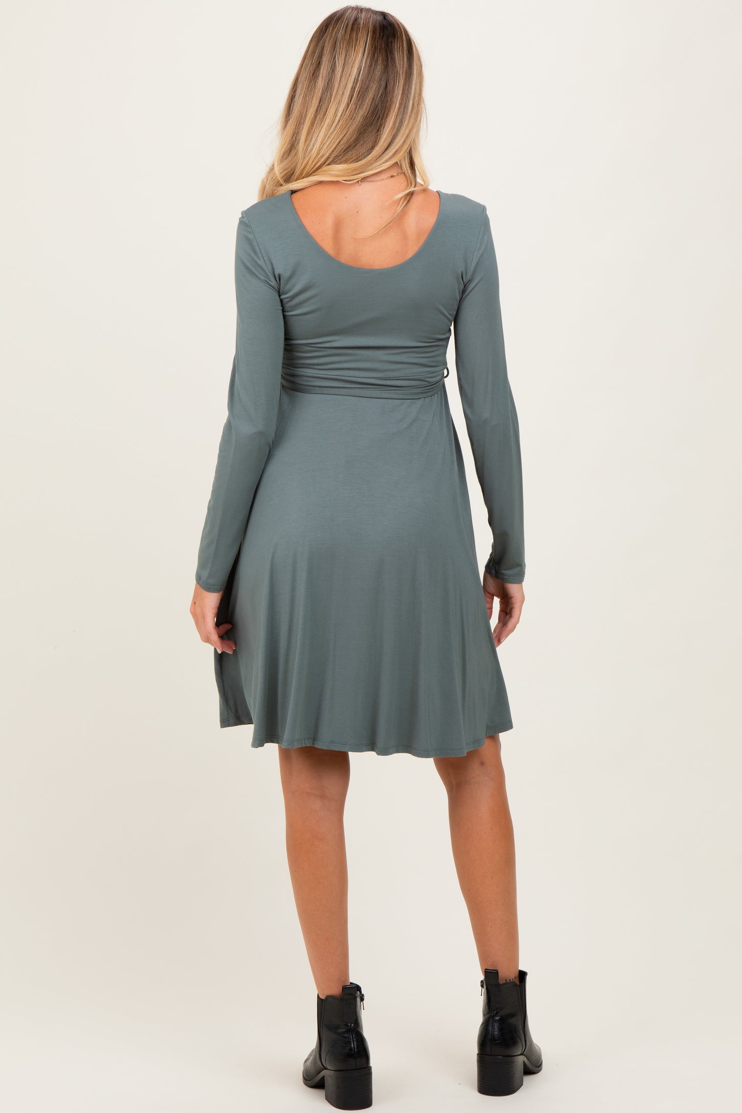 woman wearing a long sleeve green maternity dress with a fit-and-flare silhouette, showing a flattering back design