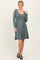 woman wearing a long sleeve sage green dress with a scoop neckline and a tie belt at the waist
