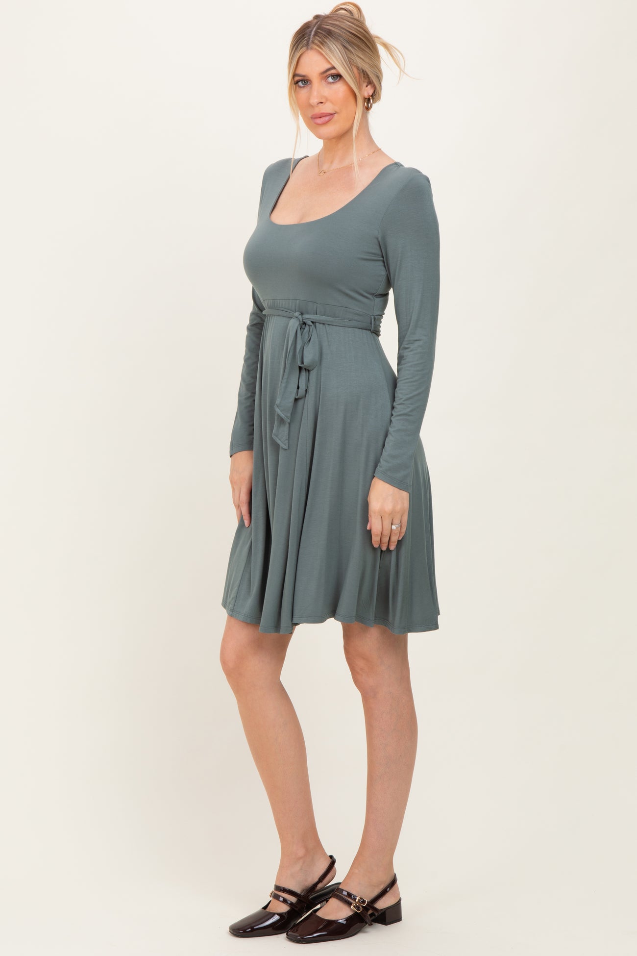woman wearing a teal long sleeve wrap dress with a tie belt and a flared skirt