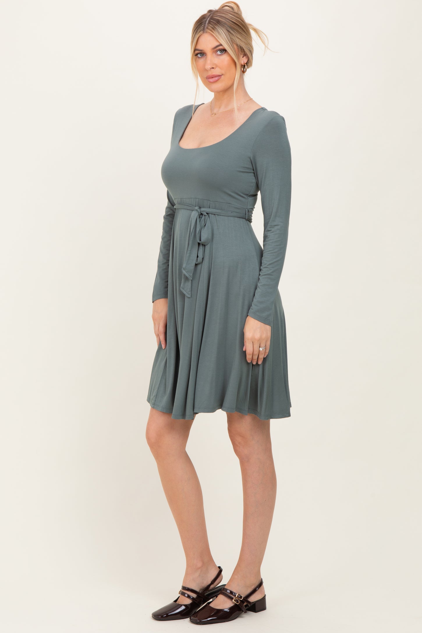 woman wearing a teal long sleeve wrap dress with a tie belt and a flared skirt