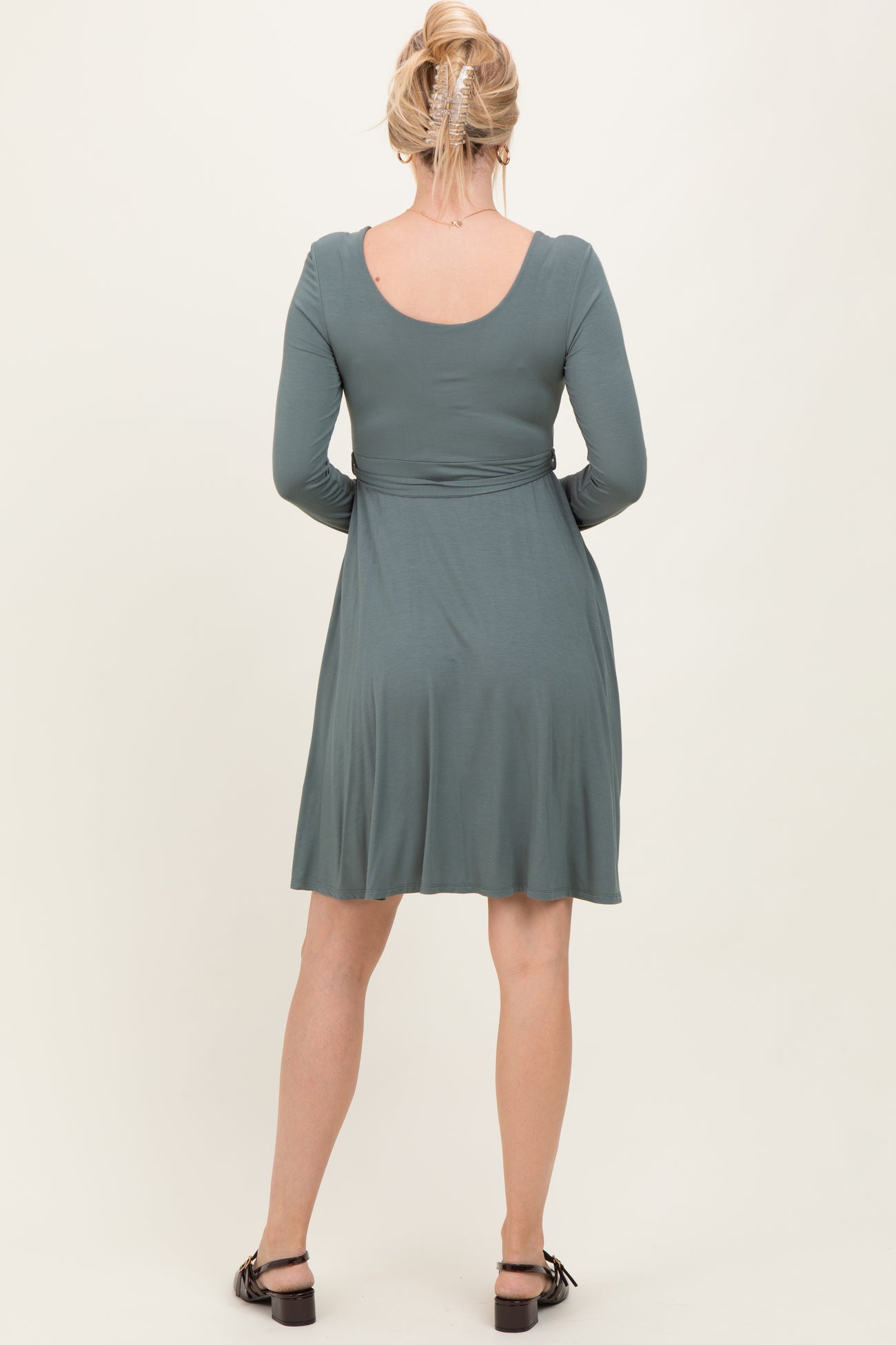 woman wearing a green long sleeve dress, showing the back view with a flared skirt and casual style