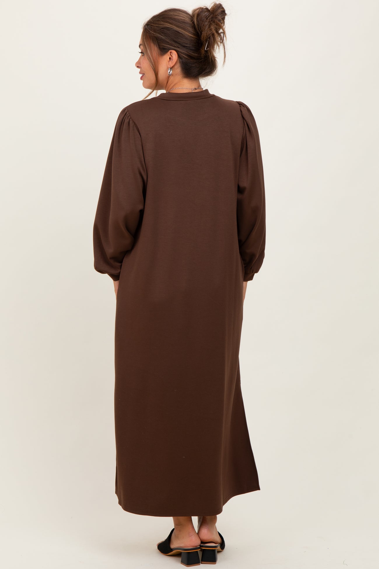 woman wearing a brown maternity maxi dress with balloon sleeves, seen from the back