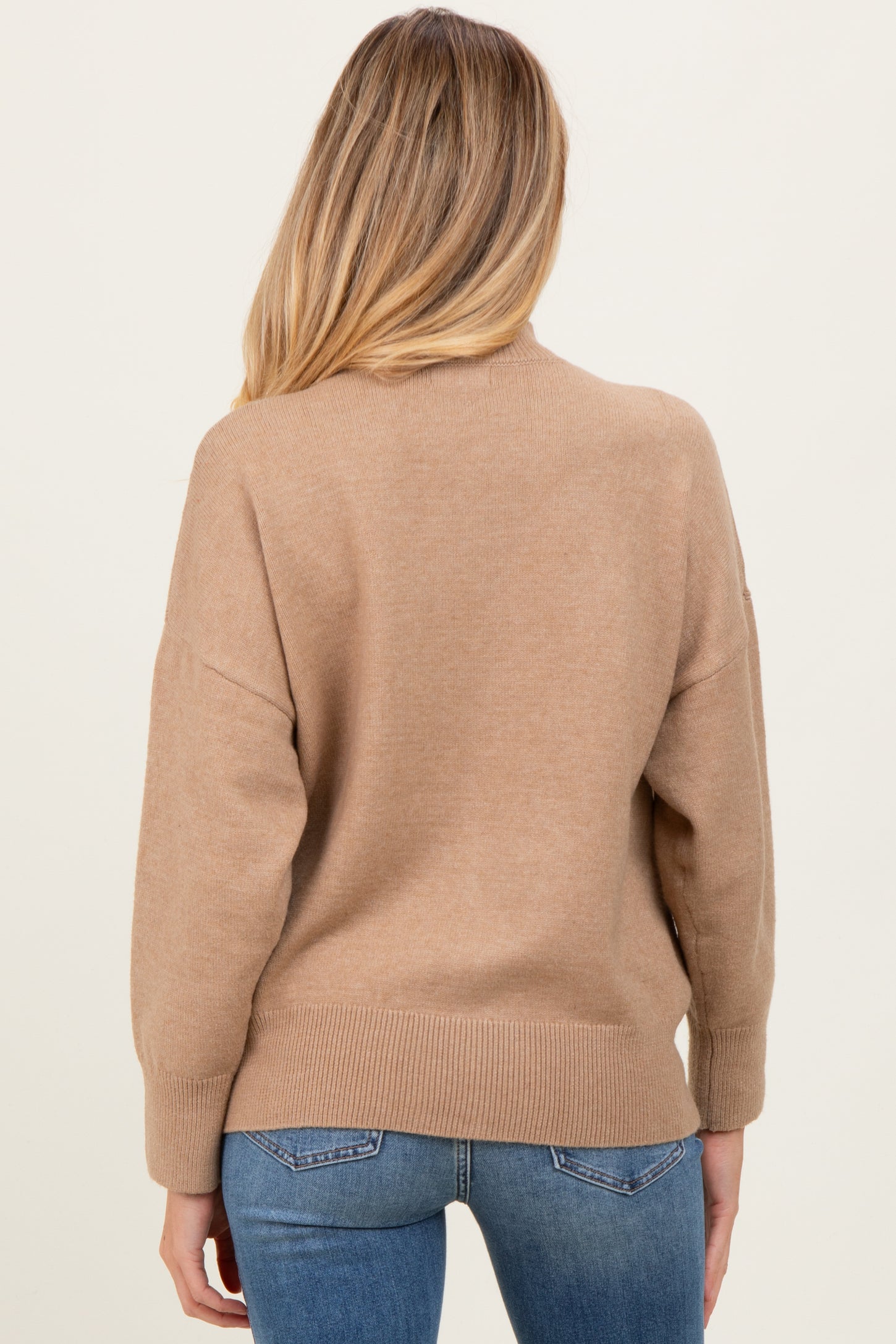 woman wearing a beige maternity sweater with a relaxed fit and ribbed hem, seen from the back
