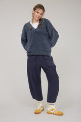 woman wearing a dark blue oversized sweater and navy wide-leg pants paired with yellow sneakers