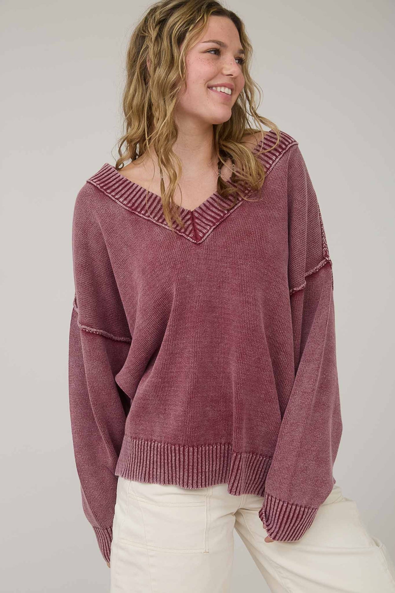 woman wearing a loose-fit maroon oversized sweater with a V-neck and contrasting ribbed hem