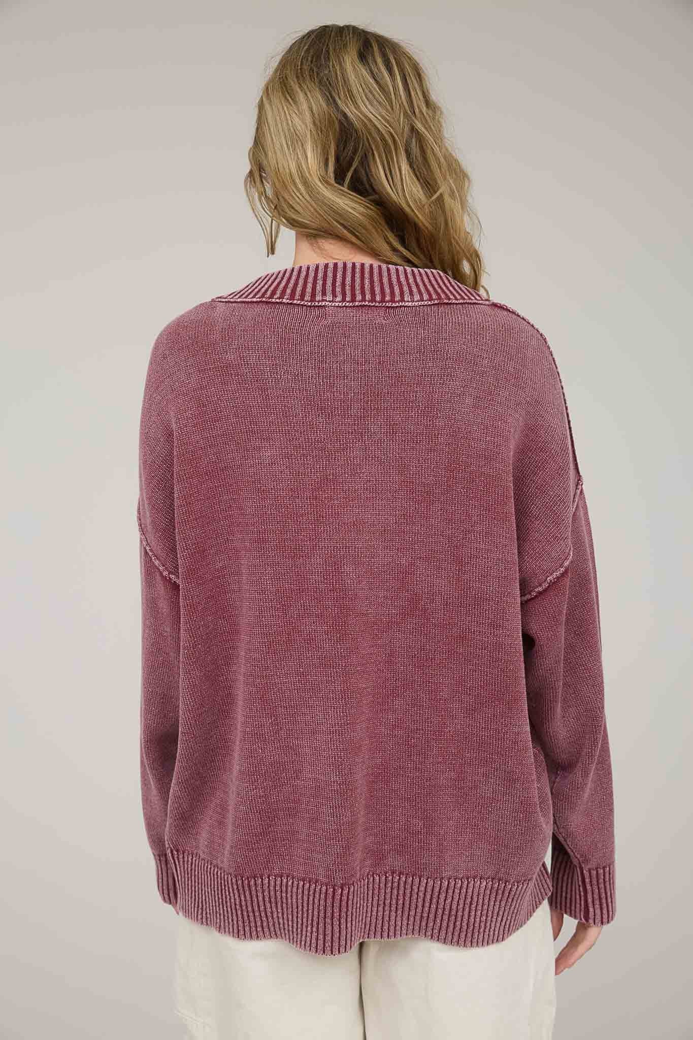 woman wearing a back view of a loose-fitting mauve sweater with a ribbed collar and cuffs